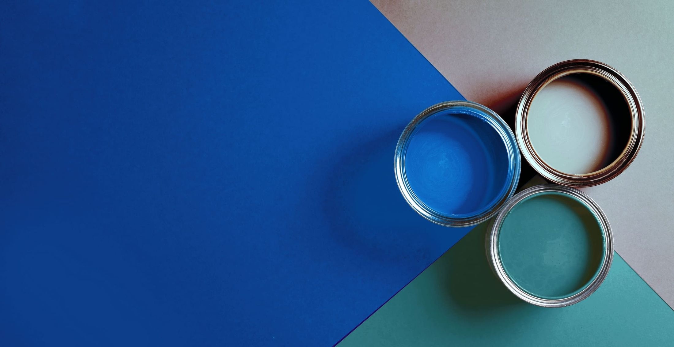 Farbpalette mit geöffneten Farbdosen in Blau- und Grüntönen - Malerbetrieb Volkmann